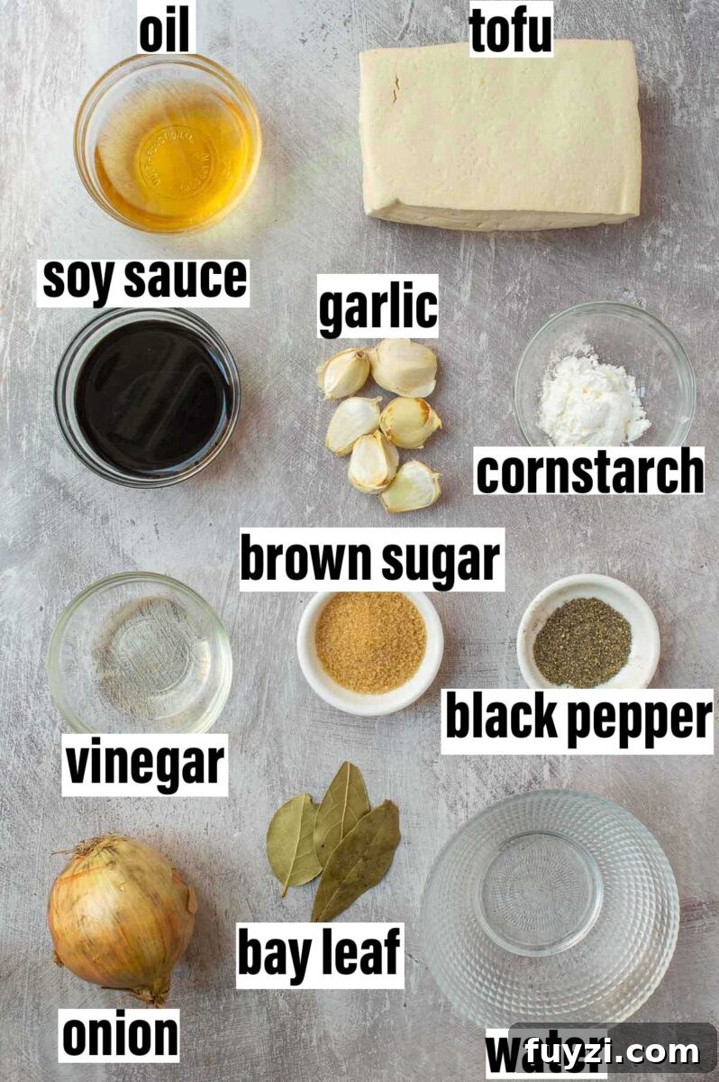 Filipino-Style Vegan Tofu Adobo Recipe 3 Labeled ingredients including oil, tofu, soy sauce, garlic, cornstarch, and bay leaves.