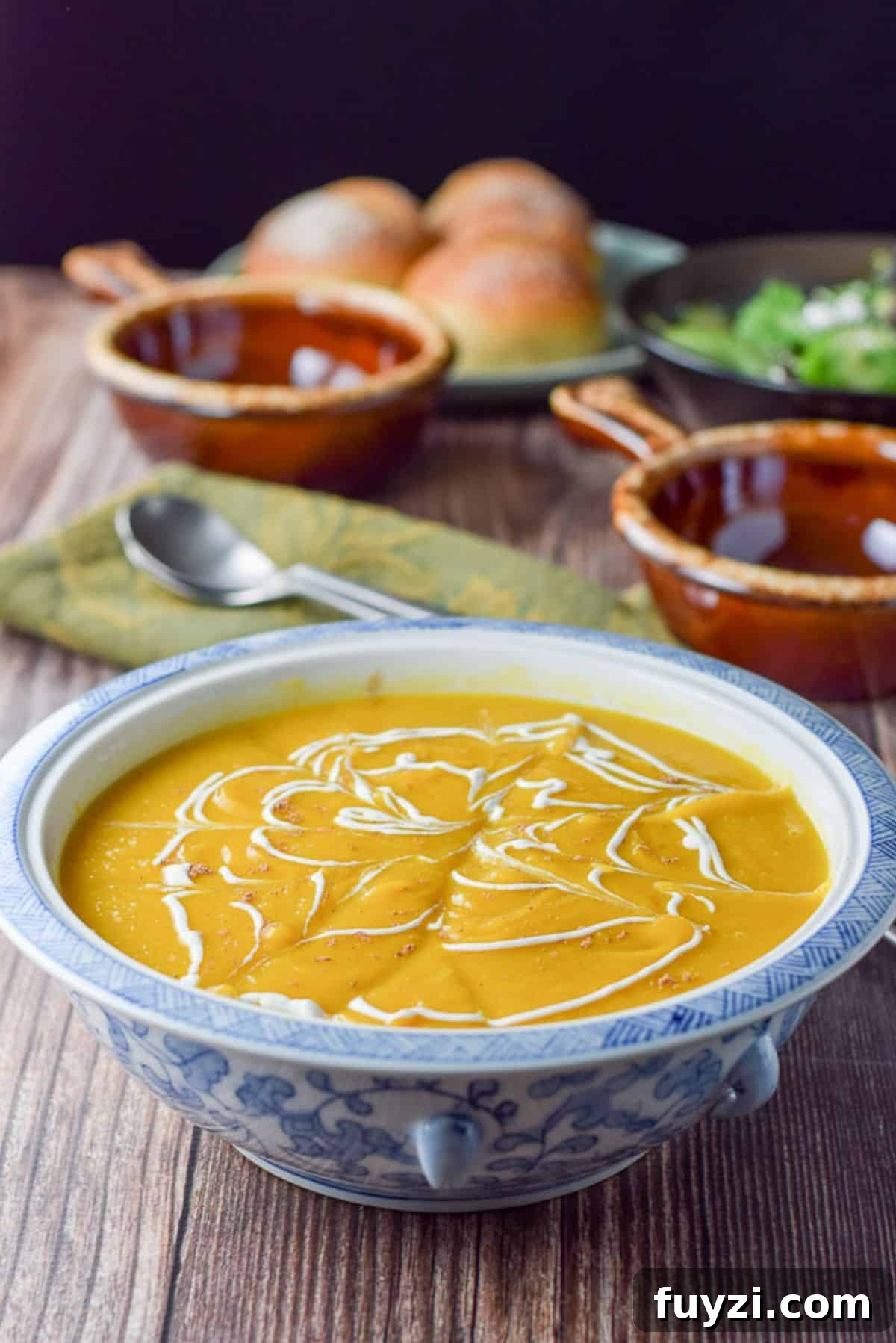 Creamy Roasted Butternut Squash Soup Recipe 6 Sour cream squiggled on the thick squash soup with crocks and rolls in the background
