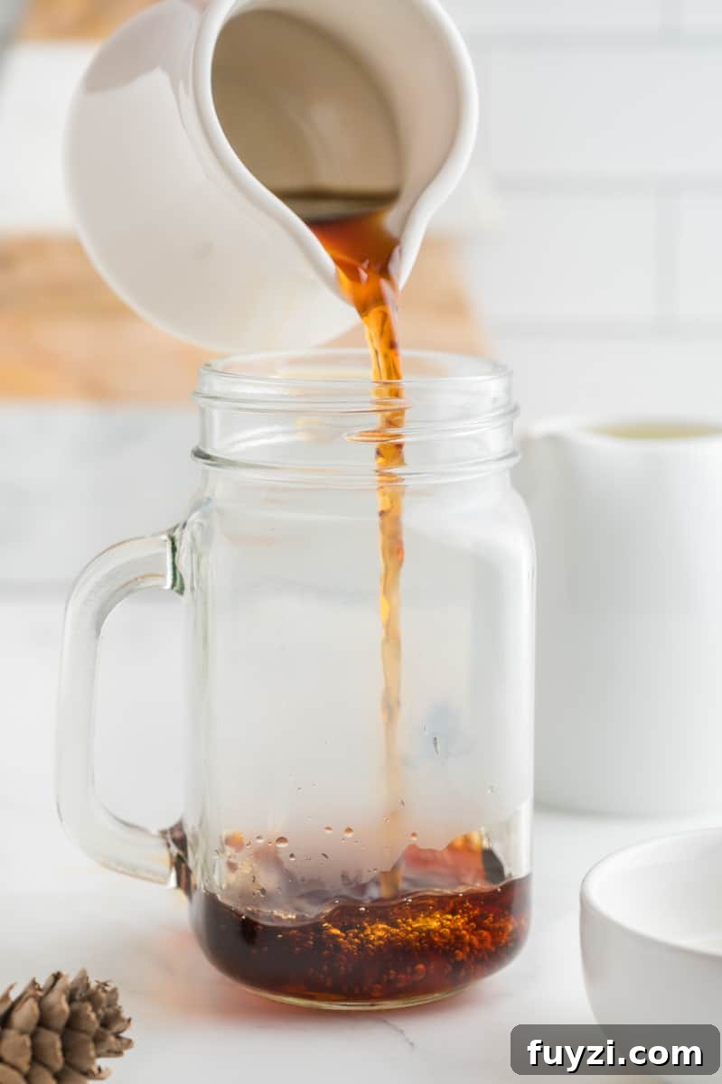 A pitcher pouring espresso into a mug.