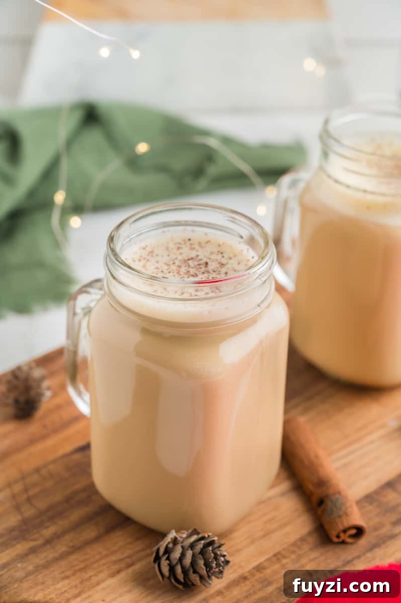 Eggnog latte surrounded by twinkly lights, a green napkin, and pine cone.