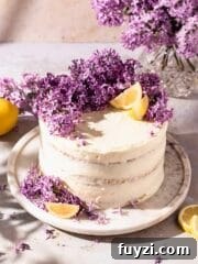 Semi naked layer cake topped with fresh lilacs and lemon wedges
