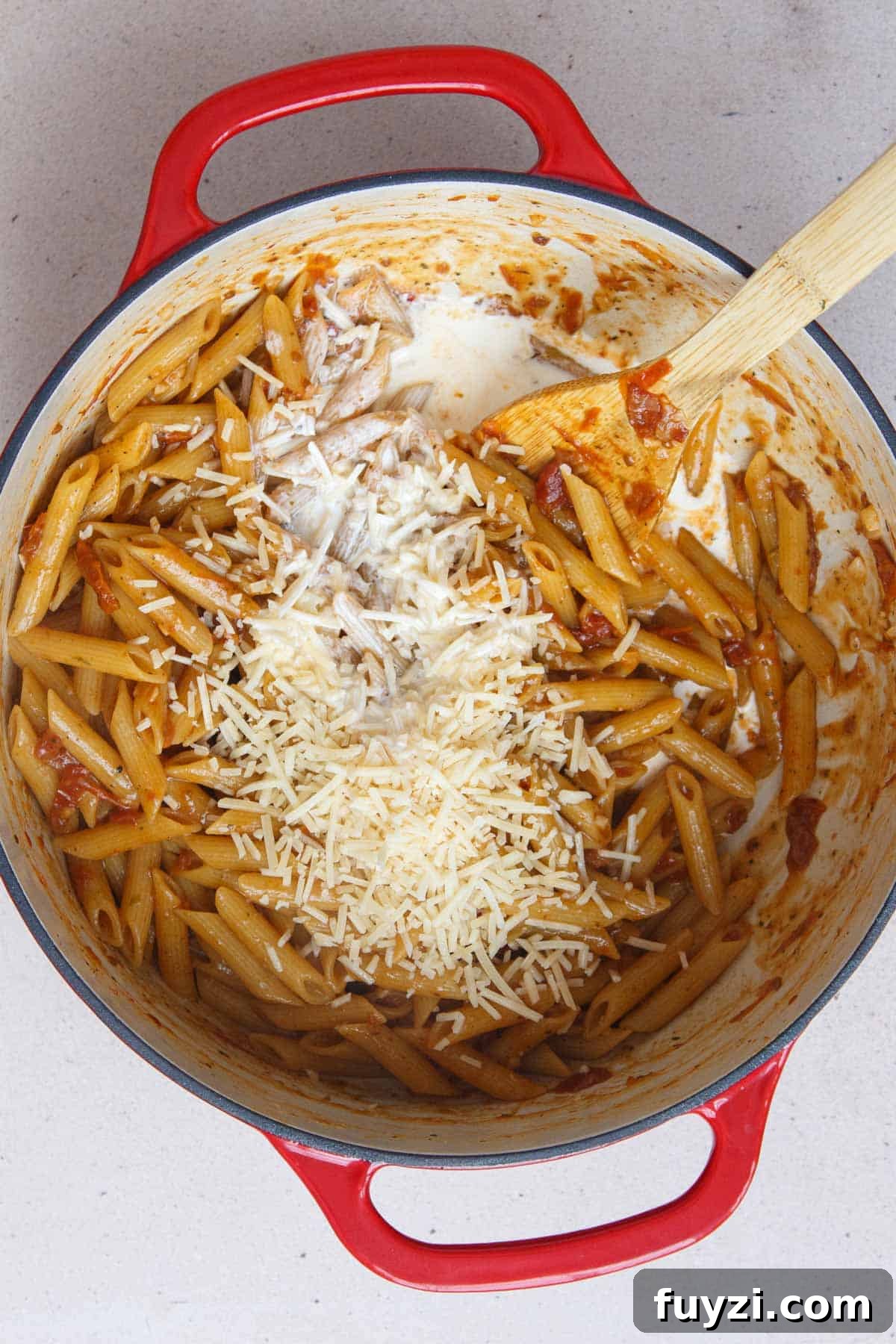 Adding parmesan and heavy cream to the penne mixture