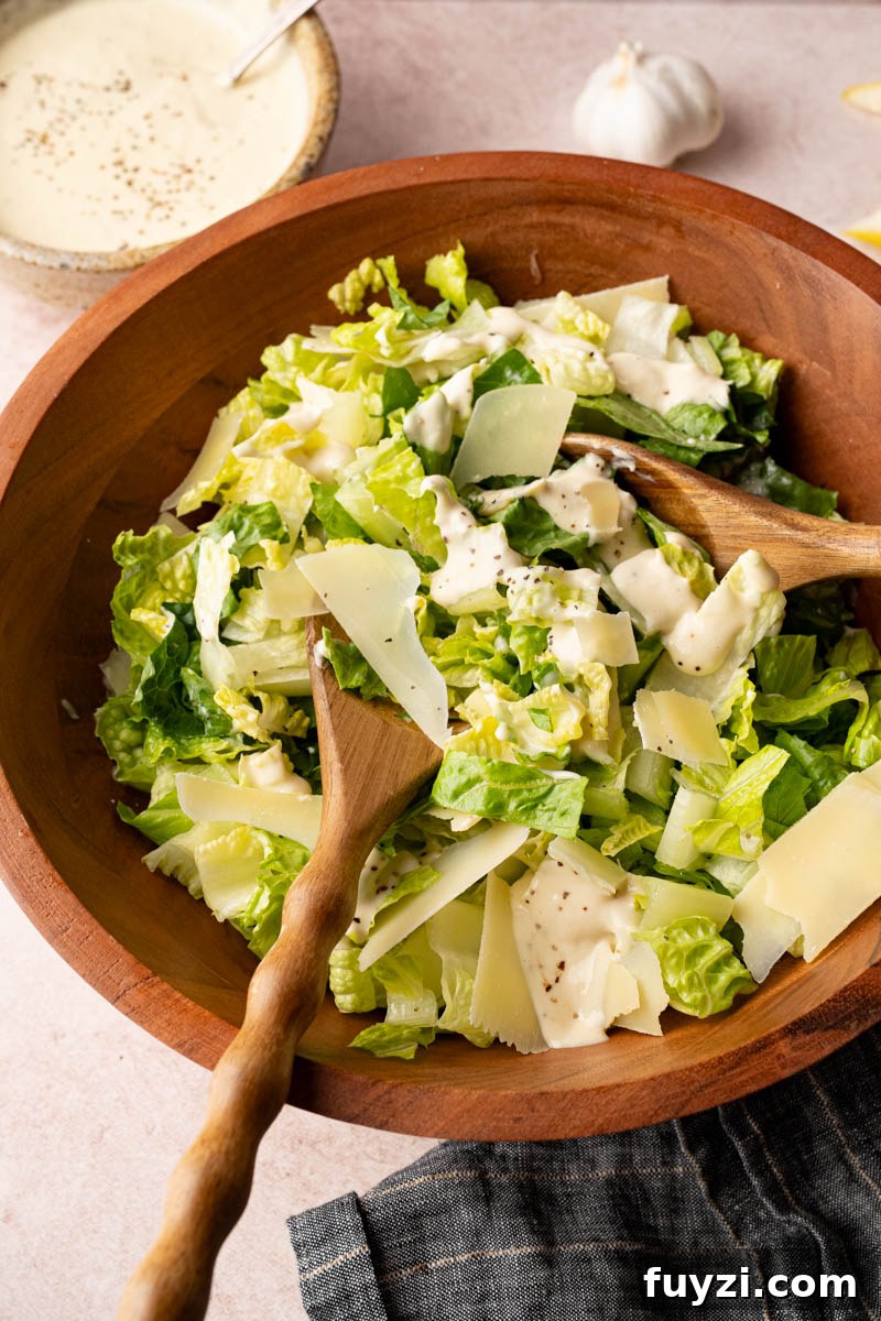 Classic Caesar Salad Recipe with Homemade Dressing 4 Tossing together the romaine lettuce, parmesan cheese and homemade caesar dressing in a wooden bowl before serving.