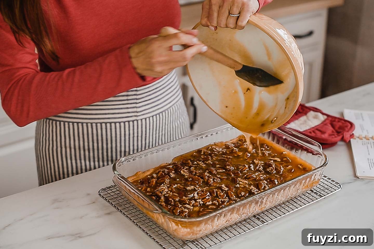 Pecan Pie Bars Recipe: Buttery Shortbread Squares 4 A woman pouring pecan pie filling over crust.