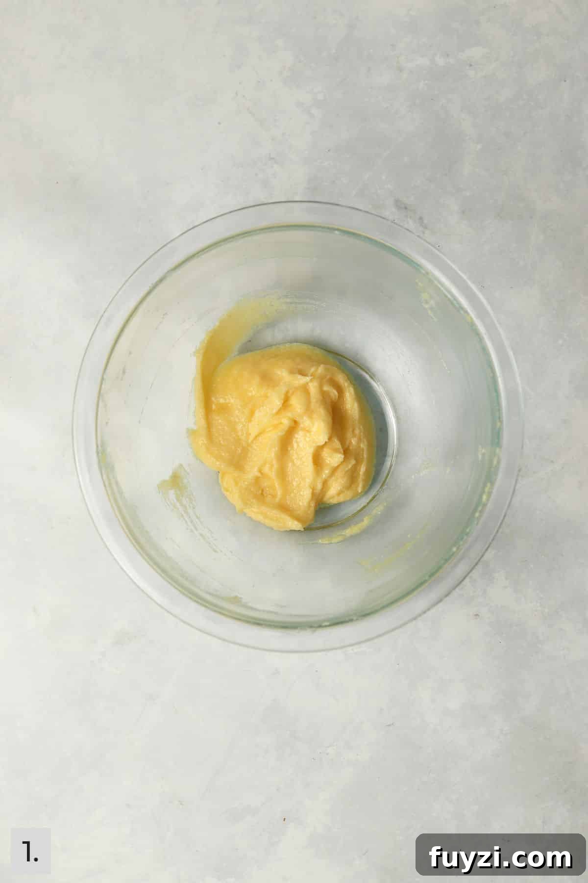 Butter mixed with sugar and an egg yolk in a mixing bowl.