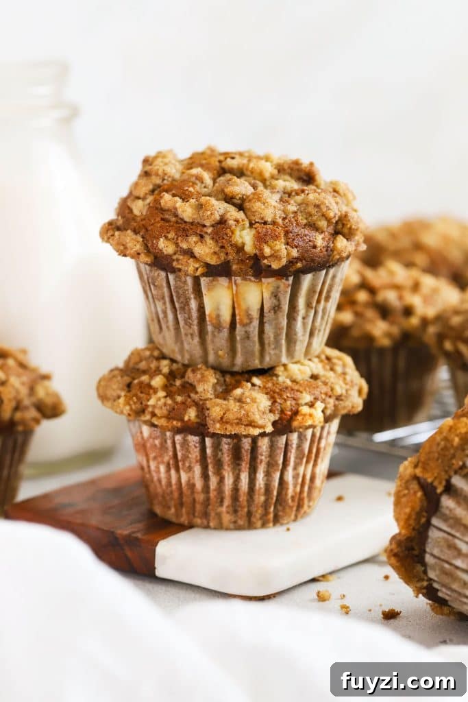 Two pumpkin cream cheese muffins stacked next to a bottle of milk