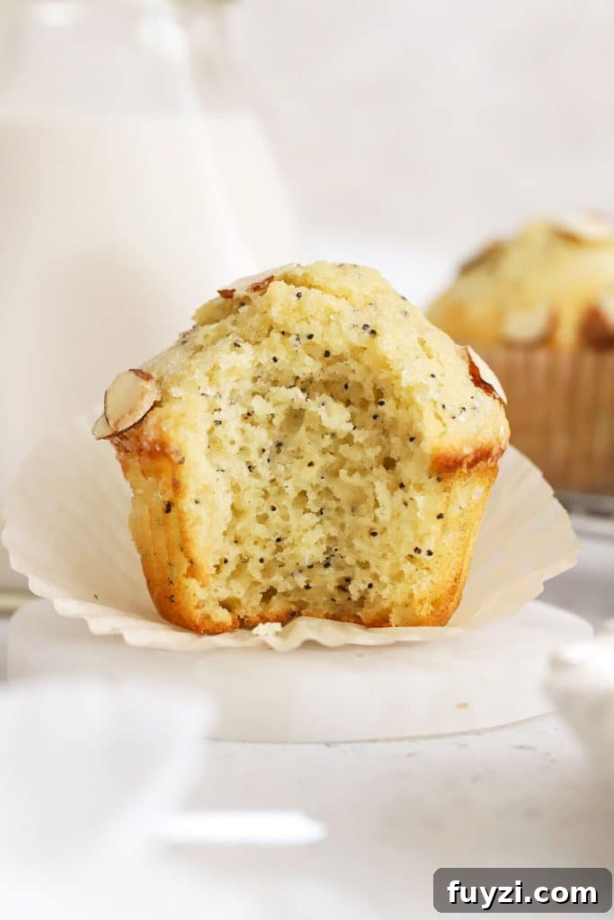 a gluten-free almond poppy seed muffin with a bite taken out of it to show the fluffy texture