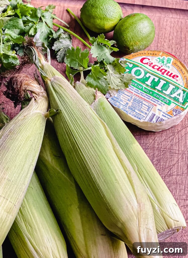 corn on the cob sitting on a cutting board with cotija cheese