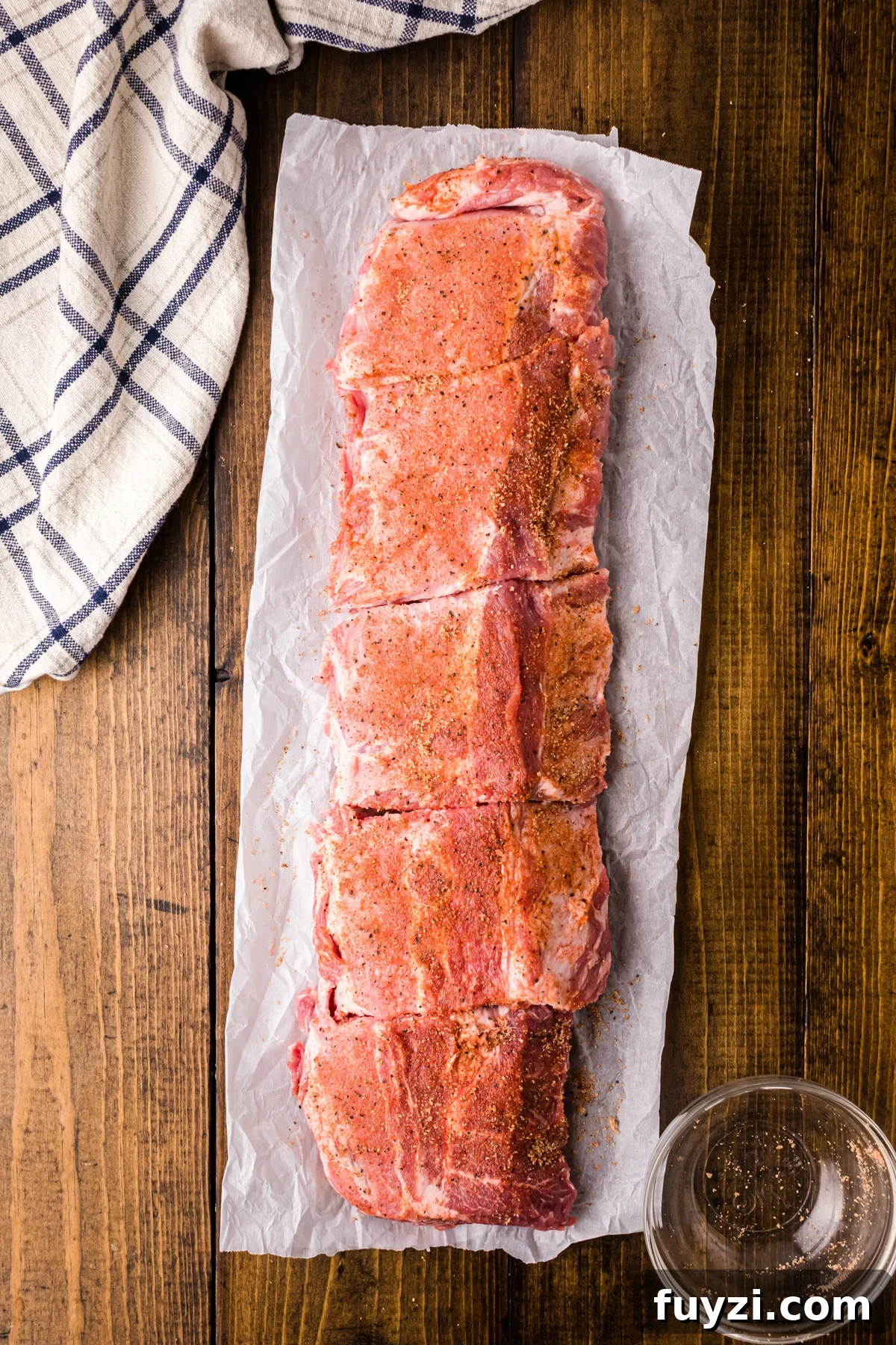 Seasoning rub on a rack of ribs separated into four pieces.