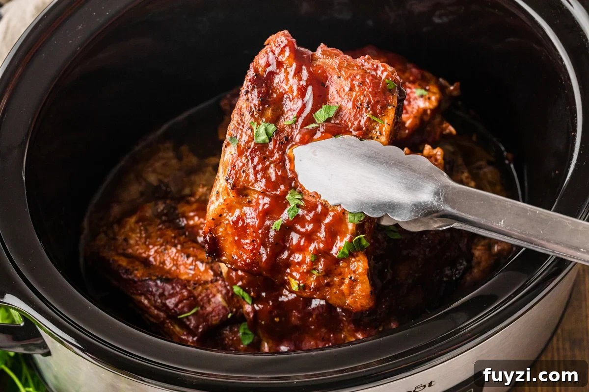 Tongs holding up a section of slow cooker baby back ribs.