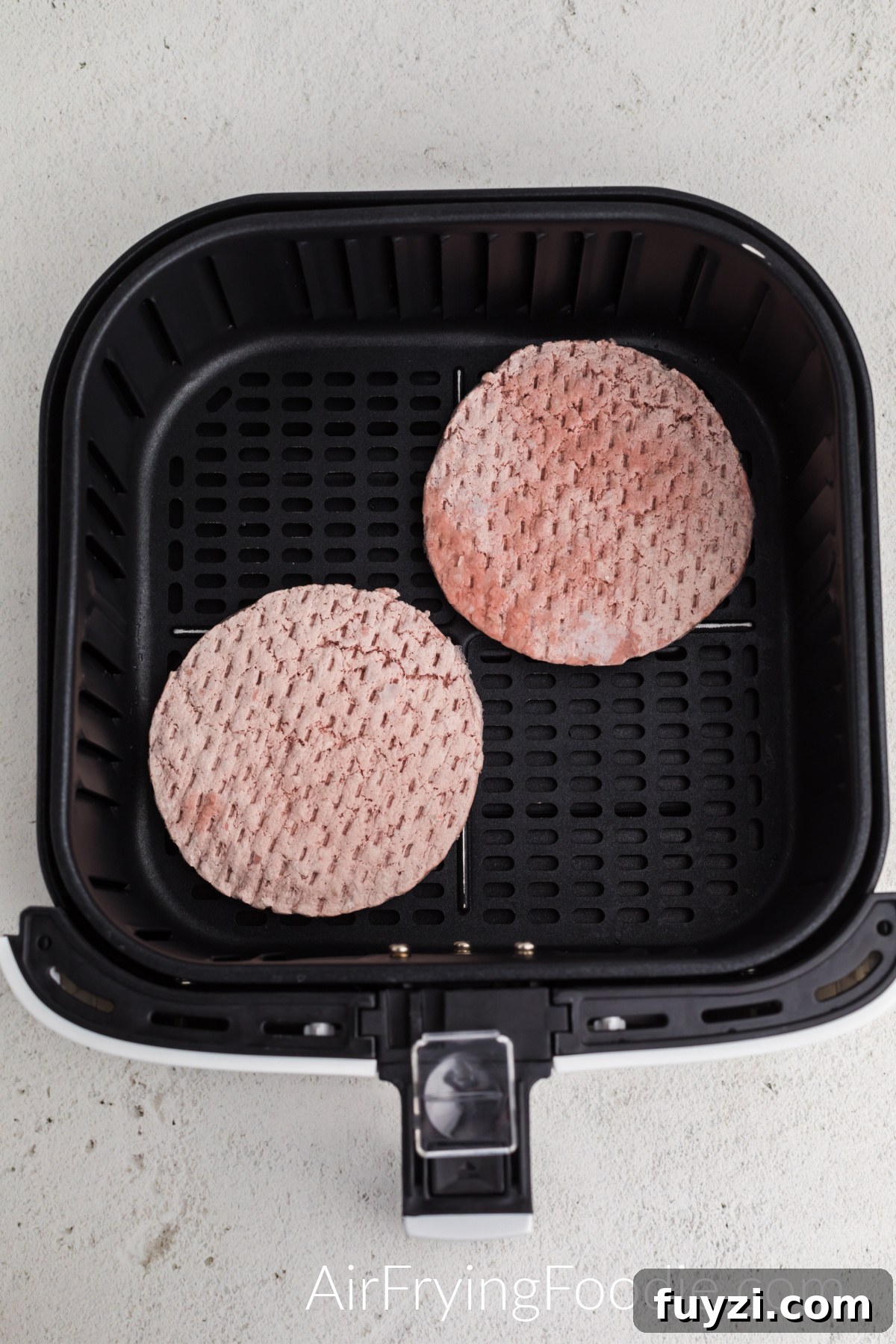 How to Cook a Frozen Burger in an Air Fryer 4 Frozen burger patties in the basket of the air fryer.