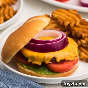 Air fryer frozen burger made with cheese and topped with onion, tomato, and lettuce.