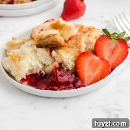 close up shot of a serving of Strawberry Dump Cake with slices of strawberry on a plate