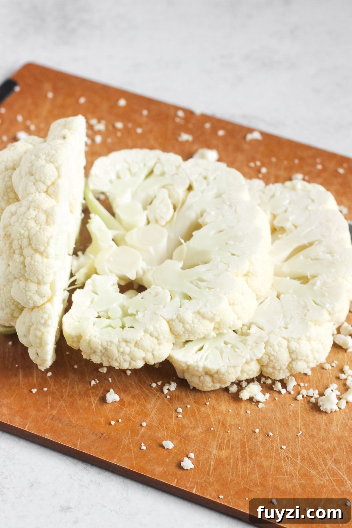 Vegan Roasted Cauliflower Steaks with Garlic-Herb Sauce 3 Sliced cauliflower steaks on a cutting board.