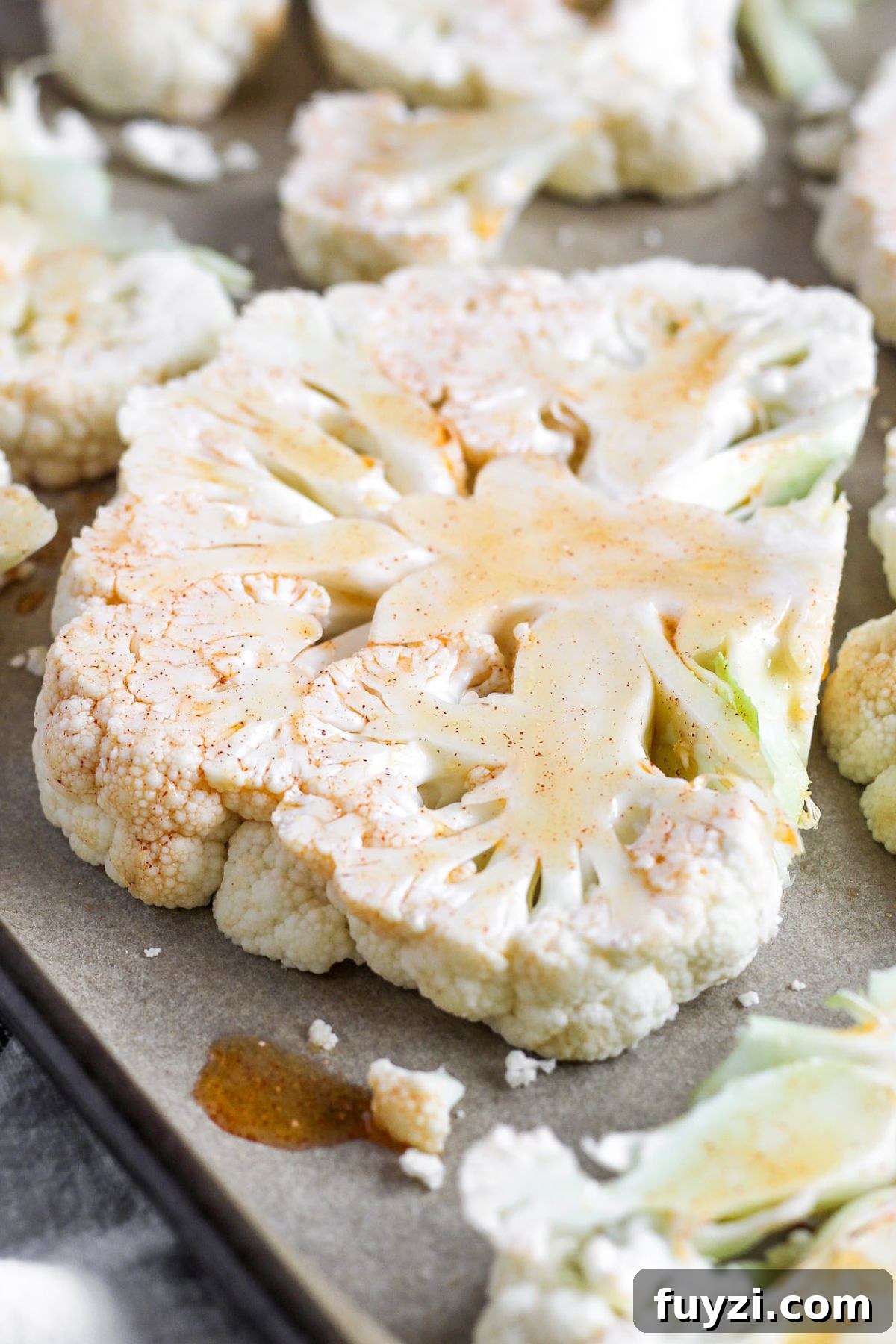 Vegan Roasted Cauliflower Steaks with Garlic-Herb Sauce 4 Raw cauliflower steaks on a baking sheet brushed with olive oil marinade.