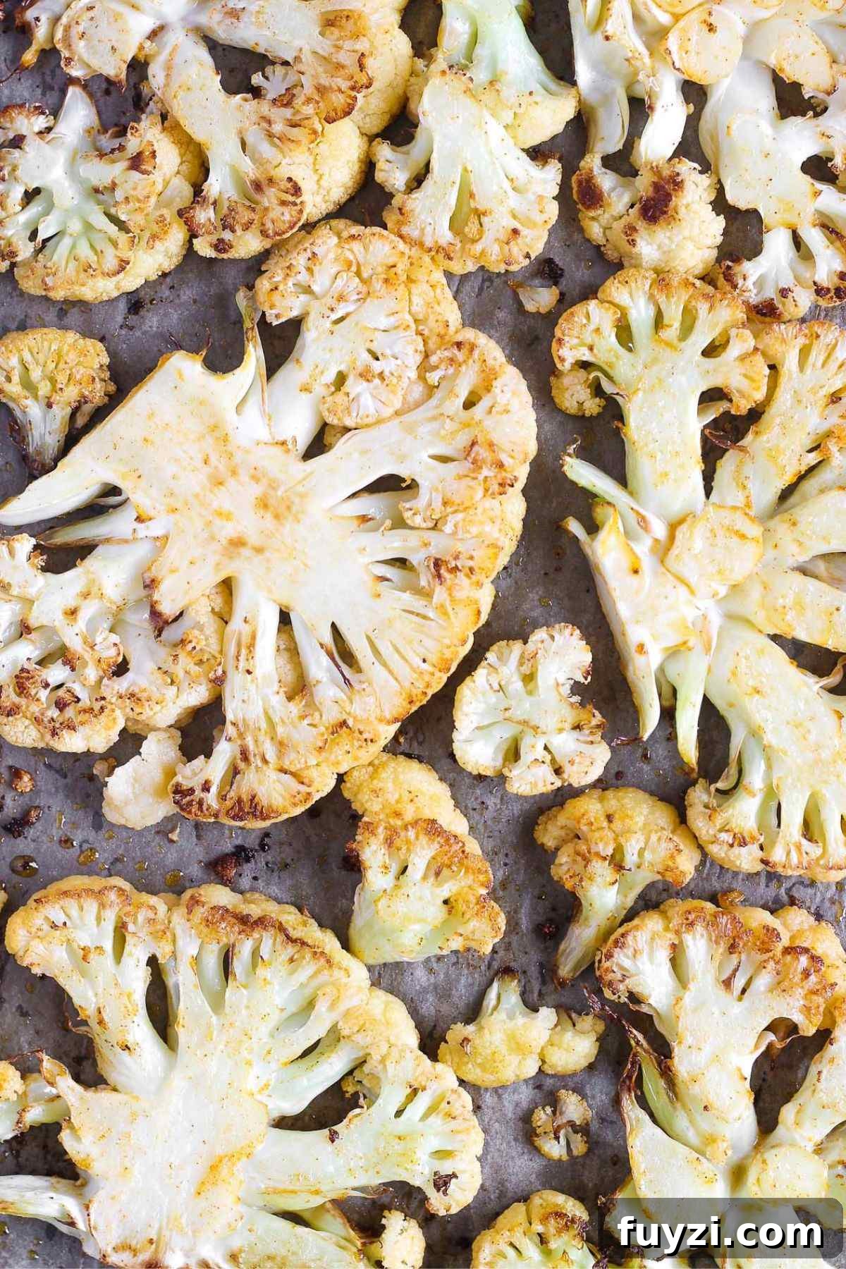 Vegan Roasted Cauliflower Steaks with Garlic-Herb Sauce 5 Roasted cauliflower steaks on a baking sheet.