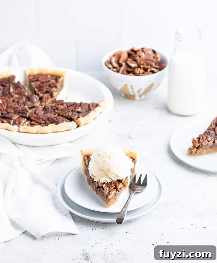 How to Make Bourbon Pecan Pie Without Corn Syrup 2 slice of bourbon pecan pie with a scoop of ice cream on top; In the background are a bowl of pecans, a glass of milk, a plated slice and the sliced pie in a white pie dish.