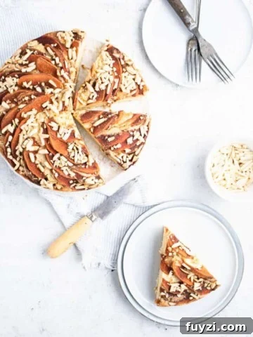 apple cake sliced with two slices still in the pan and one on a nearby blue plate.