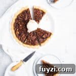 How to Make Bourbon Pecan Pie Without Corn Syrup 13 baked bourbon pecan pie sliced with a scoop of praline ice cream on top and two plated slices around it.