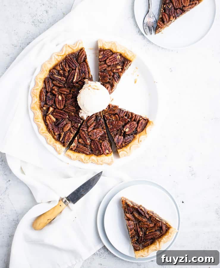 How to Make Bourbon Pecan Pie Without Corn Syrup 7 baked bourbon pecan pie sliced with a scoop of praline ice cream on top and two plated slices around it.