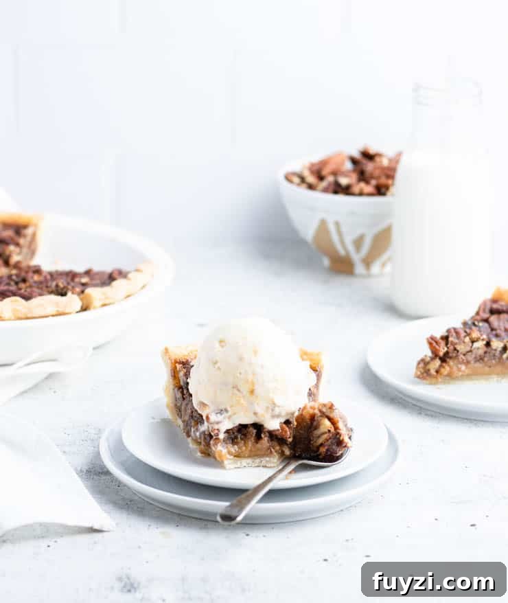 How to Make Bourbon Pecan Pie Without Corn Syrup 8 slice of bourbon pecan pie on a plate, topped with a scoop of ice cream and with a piece on a fork; In the background there's the whole pie, a bowl of pecans, a glass of milk and another plated slice.