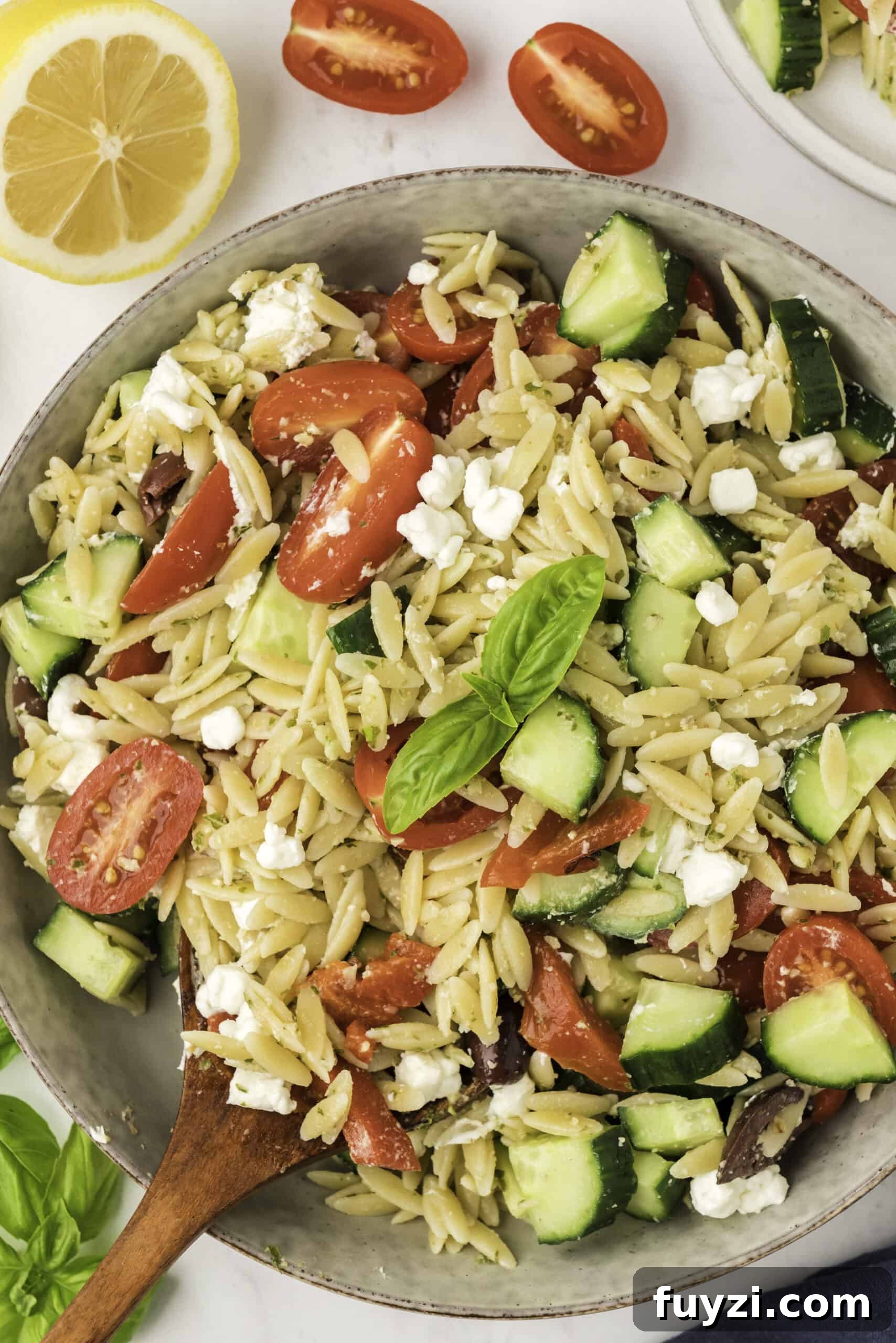 Creamy Pesto Orzo Pasta Salad with Cherry Tomatoes 7 Pasta salad out of the bowl with a wooden spoon.