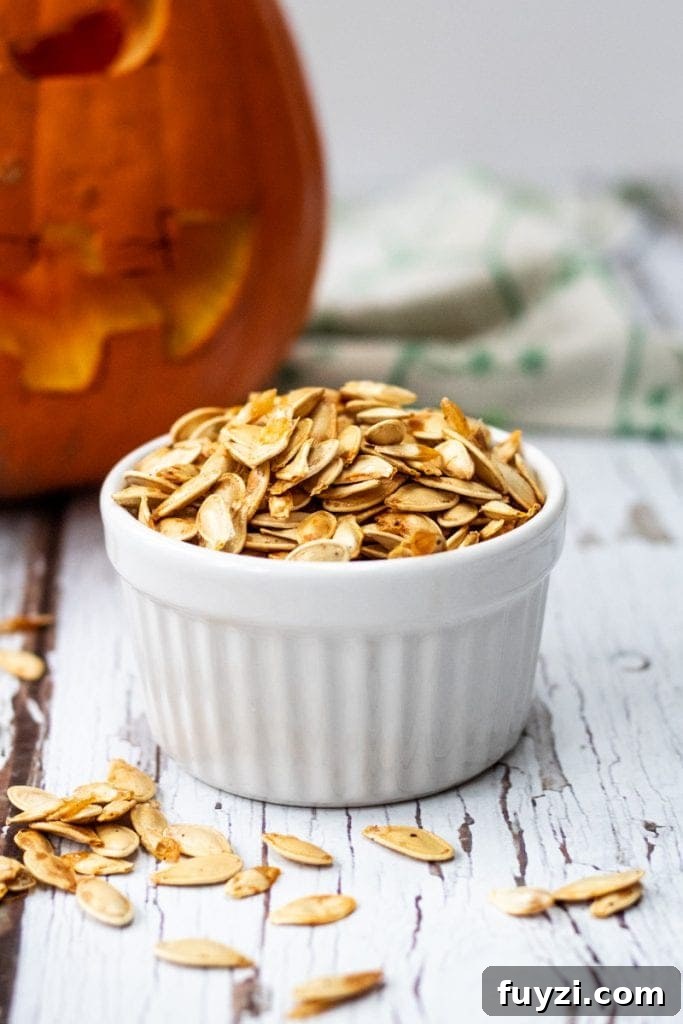 roasted pumpkin seeds in a bowl with a pumpkin in the background