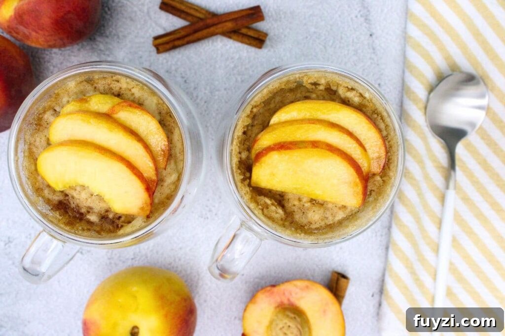 overhead view of two peach mug cake with fresh peach slices on top