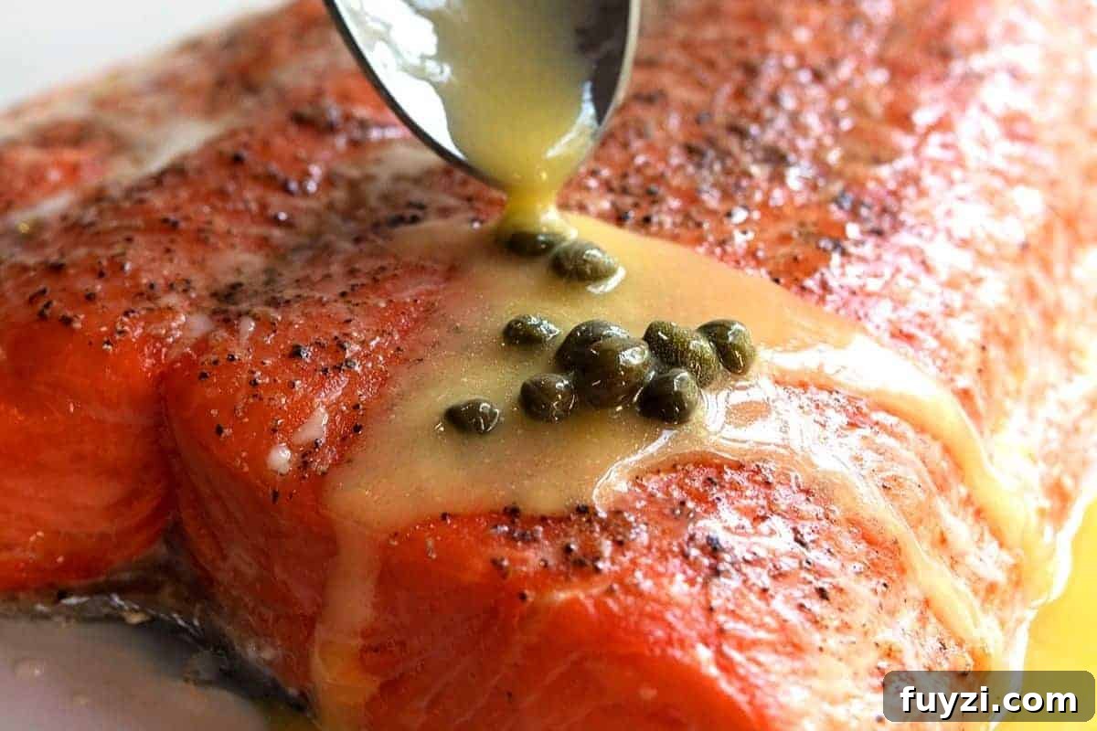 spooning lemon butter sauce with capers over salmon