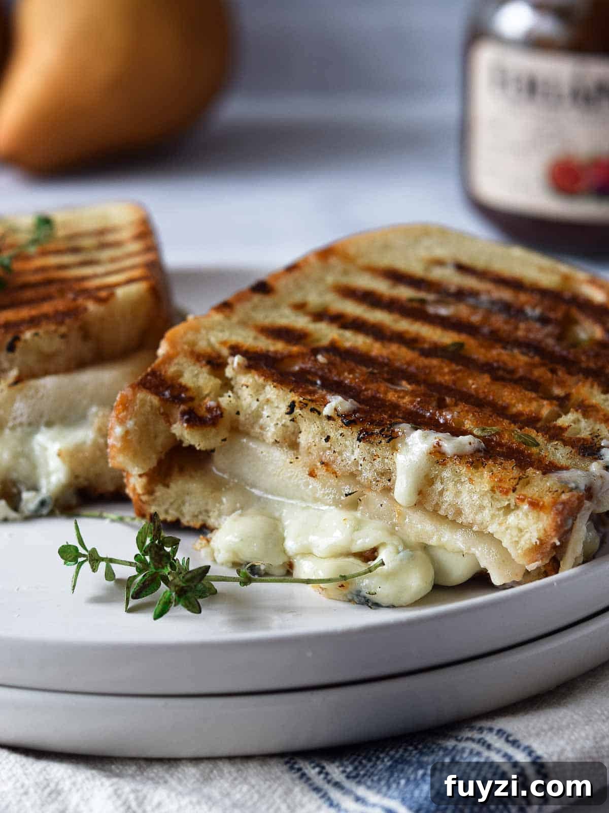 Gorgonzola and Pear Grilled Cheese Recipe with Jam 2 Gorgonzola grilled cheese cut in half on a white plate.