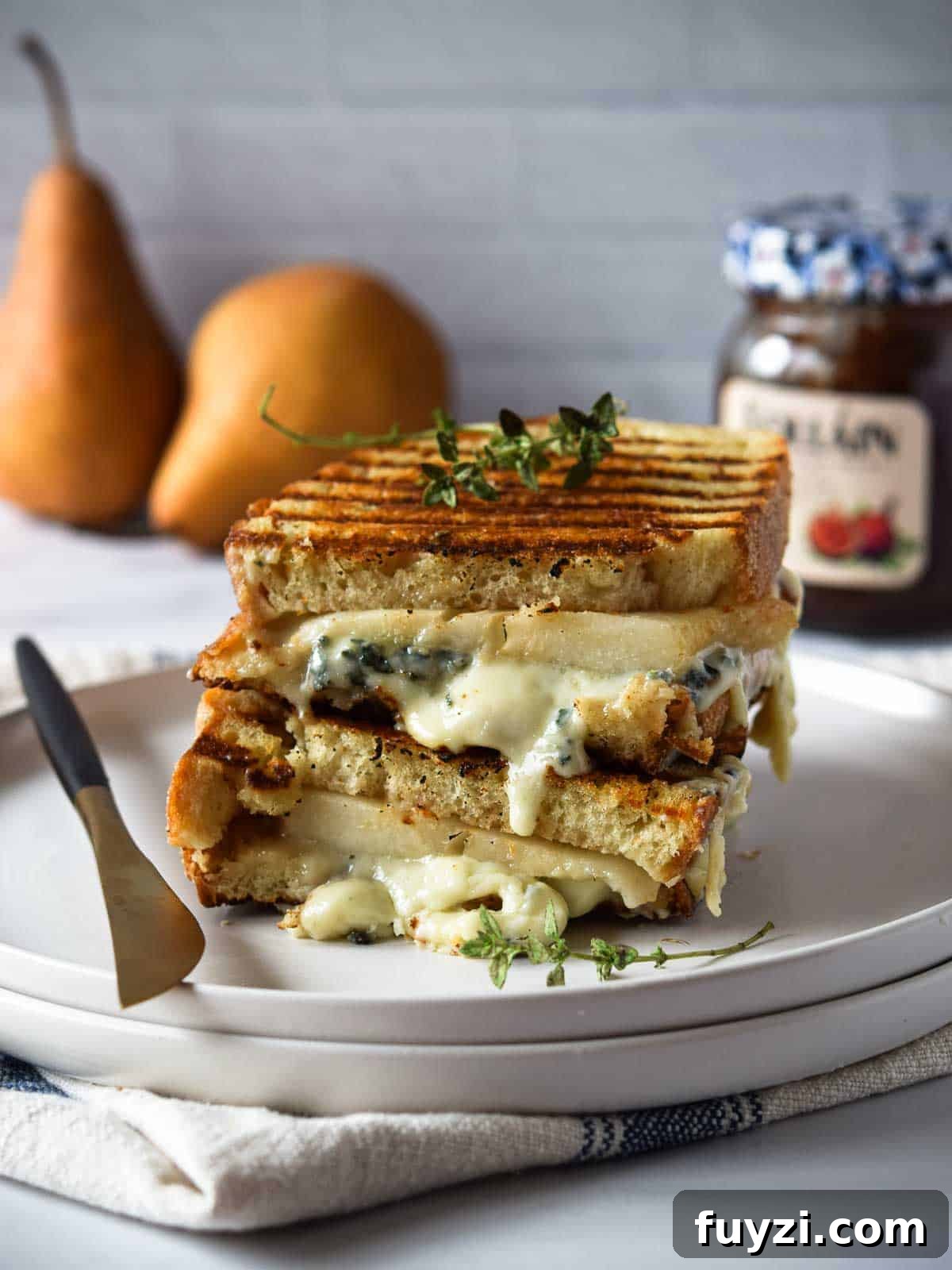Gorgonzola and Pear Grilled Cheese Recipe with Jam 3 Gorgonzola and pear grilled cheese stacked and melty on a white plate.