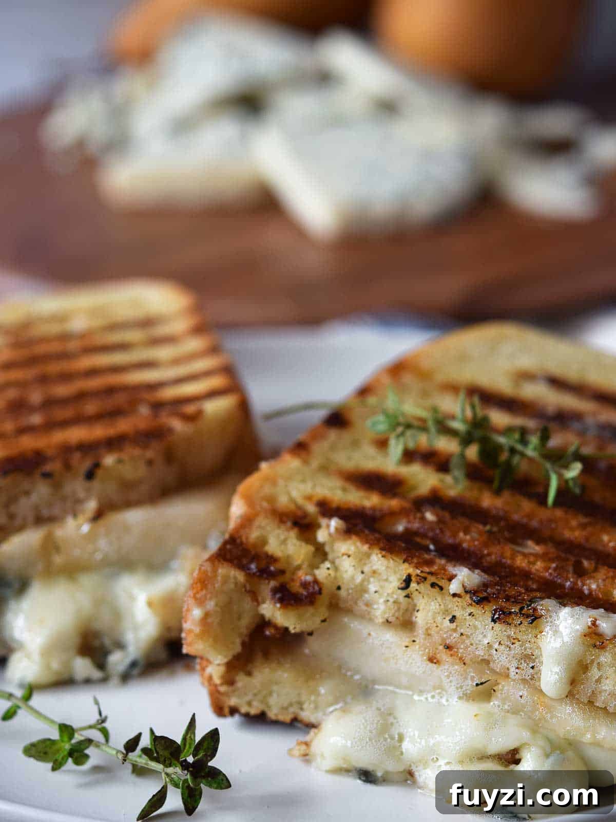Gorgonzola and Pear Grilled Cheese Recipe with Jam 8 Gorgonzola grilled cheese cut in half on a white plate.