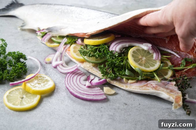 Grill a Whole Salmon: Step-by-Step Guide 6 Stuffing a whole salmon with lemon, onion, garlic, and herbs.