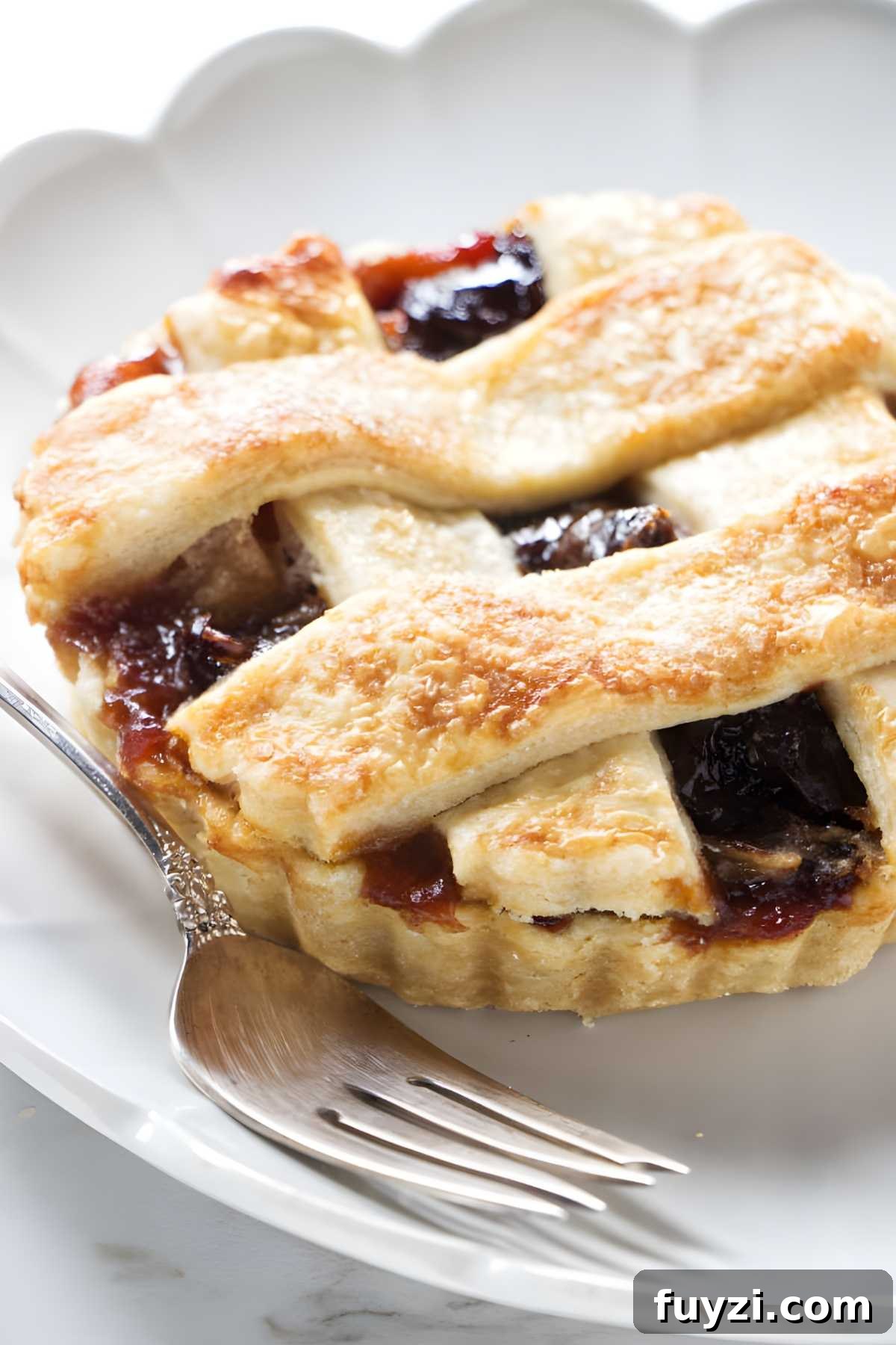Mini lattice-topped fruit tarts on white plate.