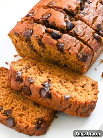 Half of a loaf of pumpkin chocolate chop bread sliced on white plate.