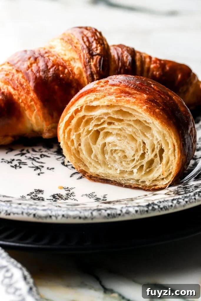 How to Make Flaky Homemade Croissants: French Recipe 3 croissant cut in half to show inside, on a plate