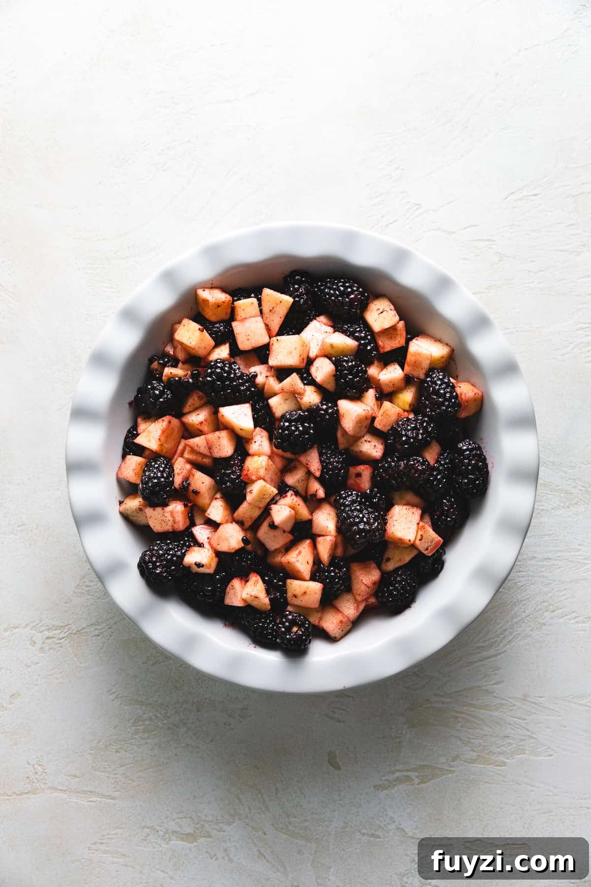 Top down view of apples and blackberries in a dish.