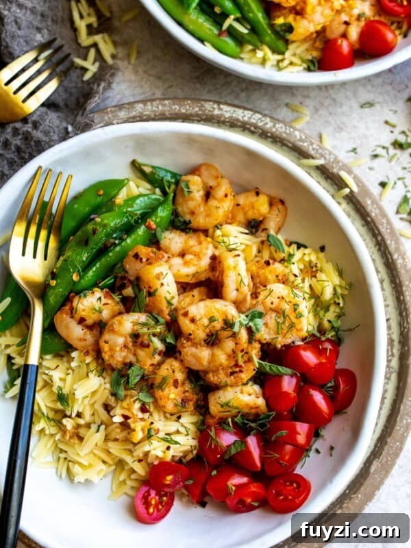 White bowl with gold fork and lemon pepper shrimp and toppings.