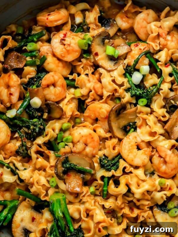 miso noodles in a skillet with broccolini and shrimp.