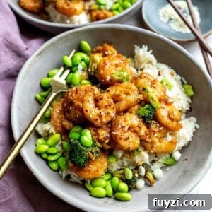 Mongolian shrimp in a grey bowl with edamame and a gold fork.