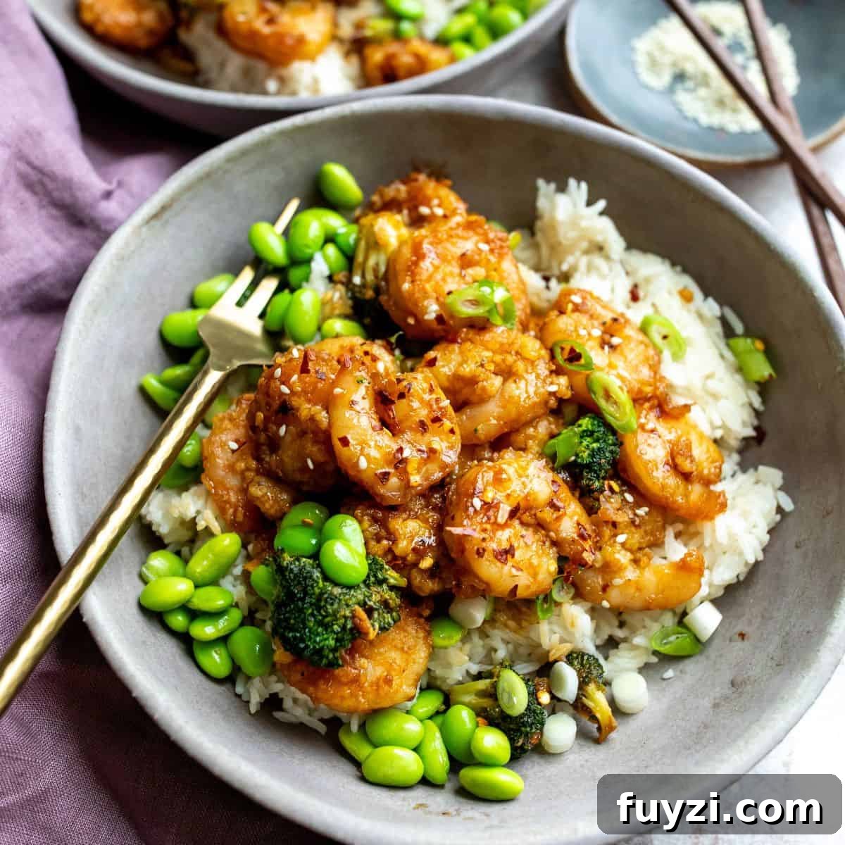 Grey ceramic bowls with rice and Mongolian shrimp with gold forks.