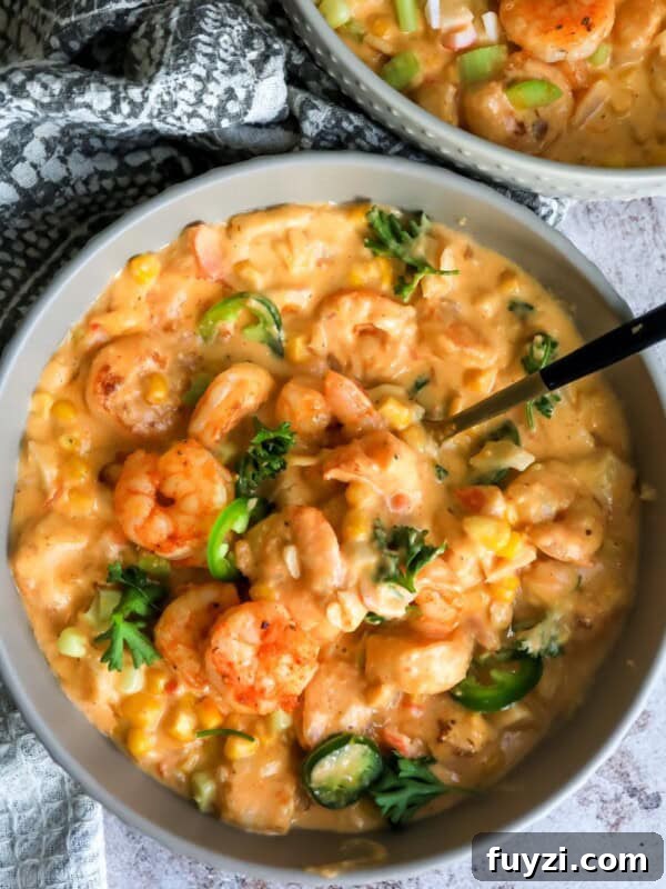 Shrimp bisque in a grey bowl with a black spoon.