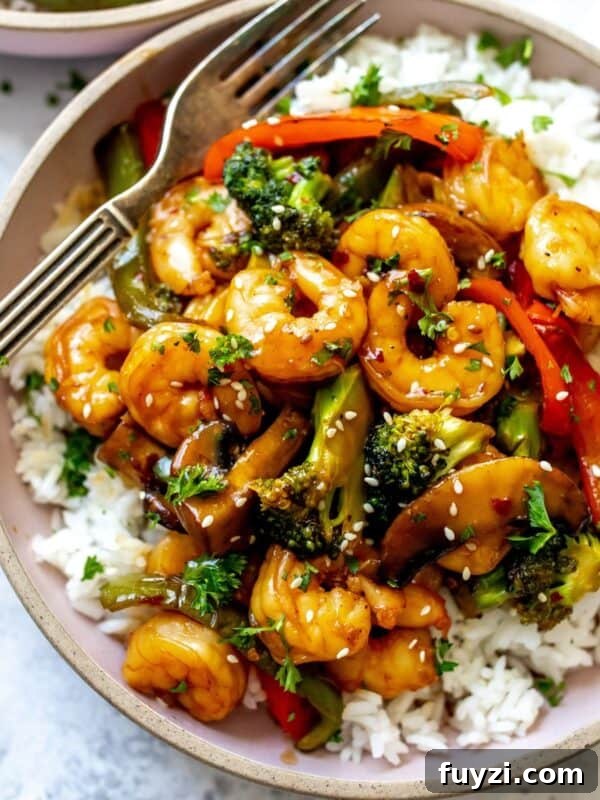 Teriyaki Shrimp and rice in a pink ceramic bowl with a fork.