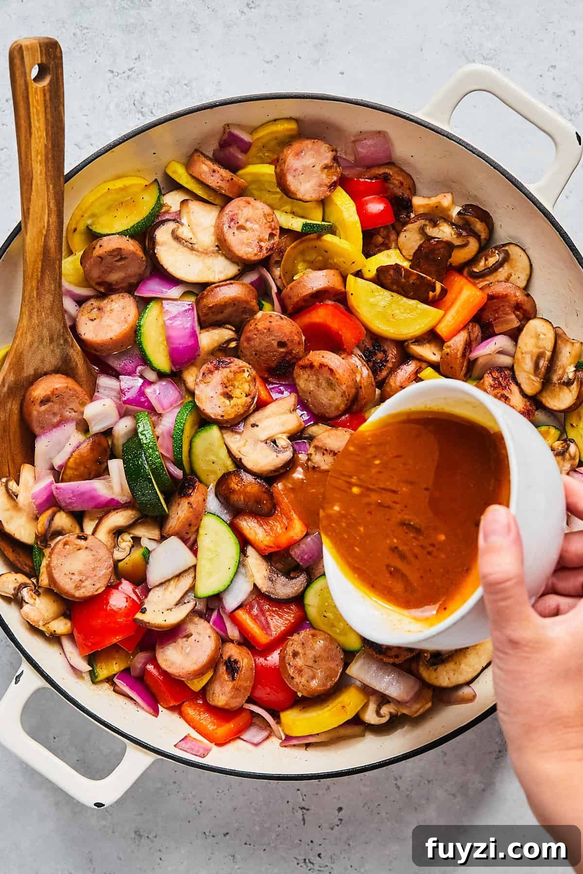 Skillet Chicken and Apple Sausage Stir Fry Recipe 9 Pouring sauce into skillet with sausage and vegetables