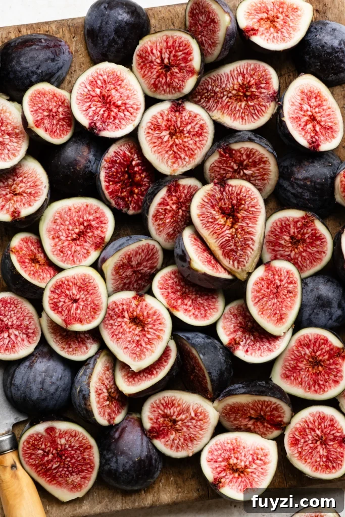 Homemade Fig Jam: Small-Batch Recipe 3 Sliced purple figs with bright pink centers layered on top of each other to cover a cuttingboard.