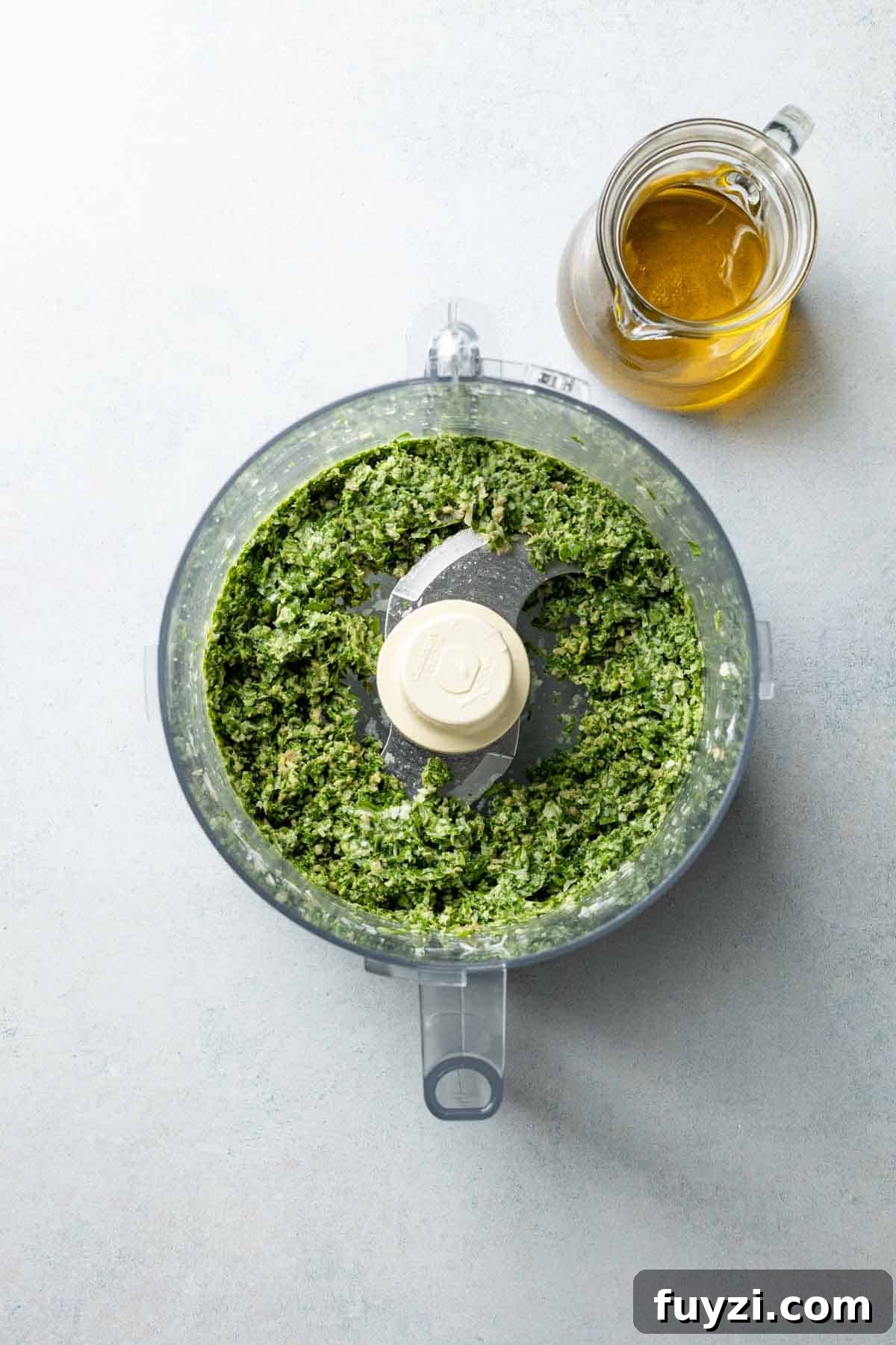 Basil, sunflower seeds, parmesan cheese, and lemon juice chopped up in food processor bowl.