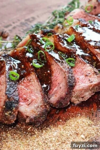 Steak topped with sauce sitting on the cutting board.