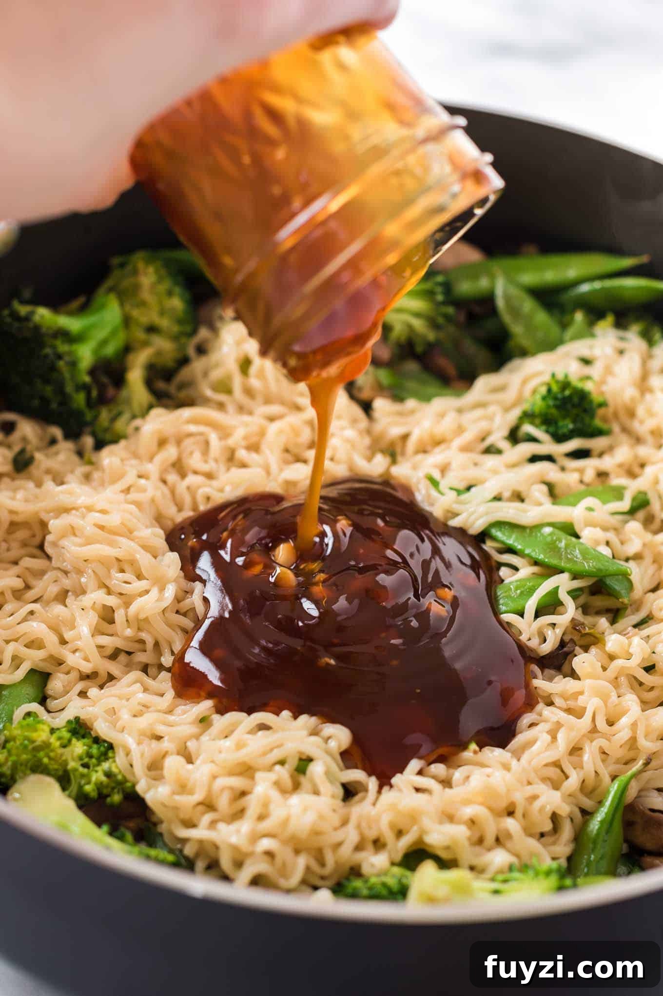 teriyaki sauce being poured onto a stir fry