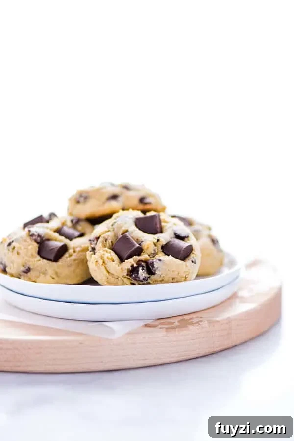 How to Feed Your Sourdough Starter and Maintain It 3 Gluten Free Sourdough Chocolate Chip Cookies on a small stack of white plates on top of a round wood cutting board