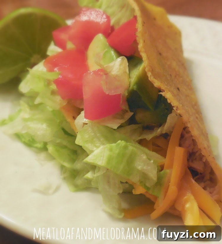 shredded pork taco with lettuce and tomato and avocado